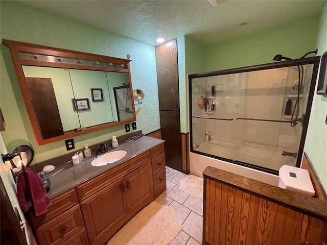 bathroom featuring combined bath / shower with glass door, a textured ceiling, vanity, and tile patterned flooring