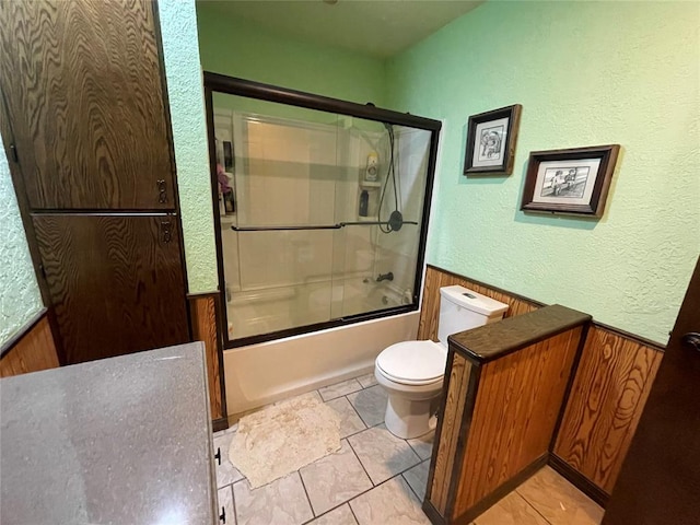 bathroom featuring combined bath / shower with glass door and toilet