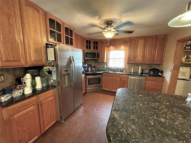 kitchen with sink, stainless steel appliances, dark stone counters, and tasteful backsplash