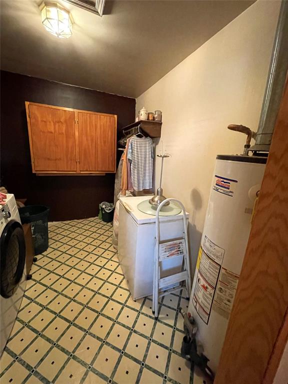 clothes washing area with cabinets, gas water heater, and washer / dryer