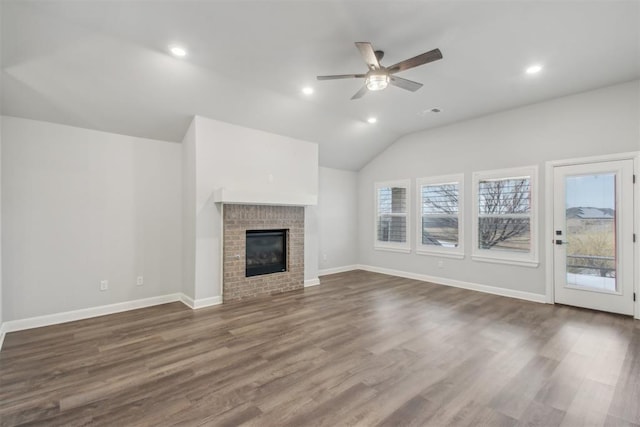 unfurnished living room with lofted ceiling, a brick fireplace, dark wood-type flooring, and ceiling fan