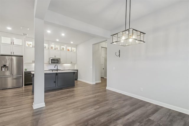 kitchen featuring white cabinetry, an island with sink, pendant lighting, stainless steel appliances, and decorative backsplash