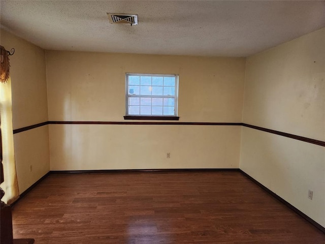 empty room with dark hardwood / wood-style flooring and a textured ceiling