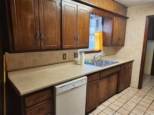 kitchen featuring tasteful backsplash, dishwasher, light tile patterned floors, and sink