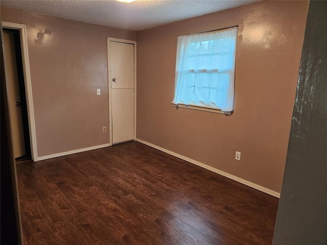 empty room featuring dark hardwood / wood-style floors and a textured ceiling