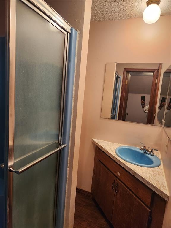 bathroom with wood-type flooring, vanity, a textured ceiling, and walk in shower