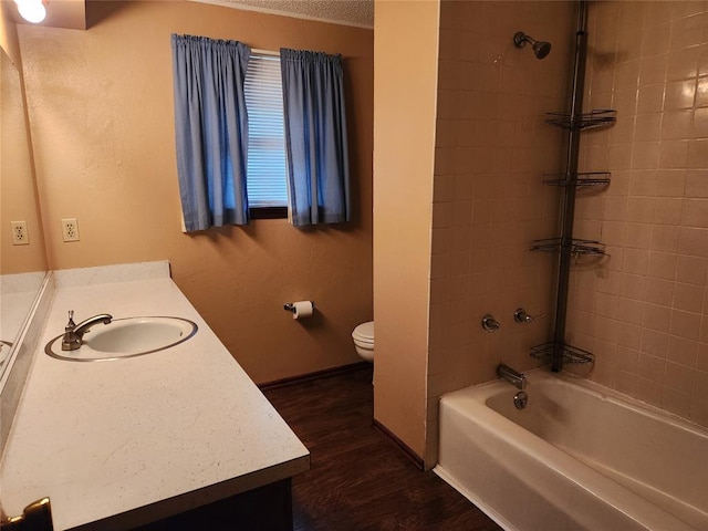 full bathroom with tiled shower / bath, toilet, vanity, and hardwood / wood-style flooring