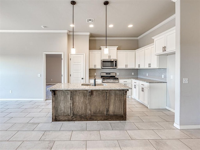 kitchen featuring appliances with stainless steel finishes, light stone counters, a kitchen island with sink, and sink