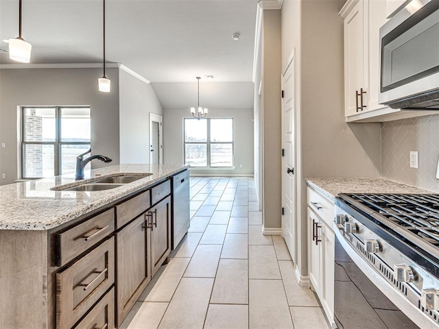 kitchen with decorative light fixtures, an island with sink, stainless steel appliances, and sink