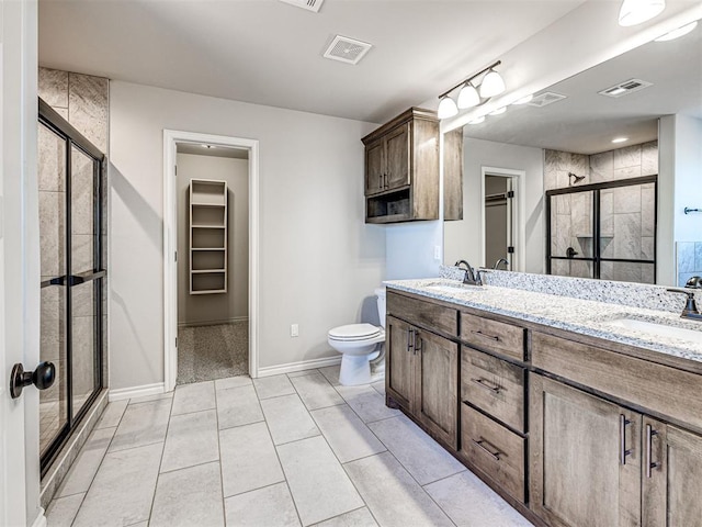 bathroom featuring tile patterned flooring, vanity, toilet, and walk in shower