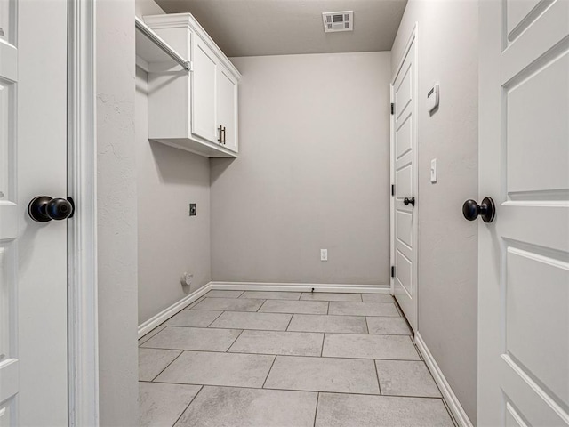 laundry room featuring electric dryer hookup, light tile patterned floors, and cabinets