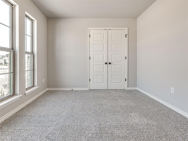 unfurnished bedroom featuring carpet flooring, a closet, and multiple windows