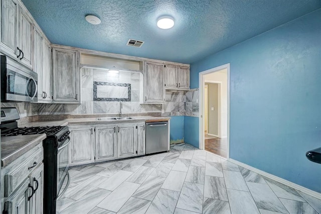 kitchen featuring tasteful backsplash, sink, a textured ceiling, and appliances with stainless steel finishes