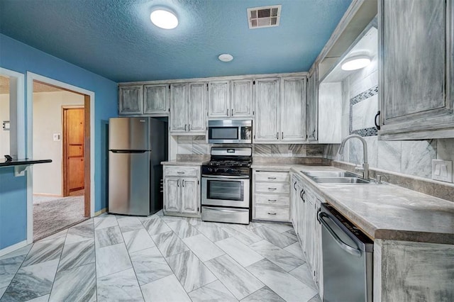 kitchen featuring appliances with stainless steel finishes, a textured ceiling, and sink