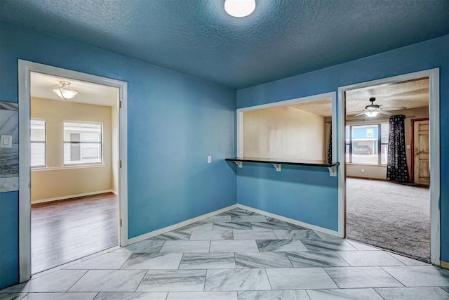 carpeted spare room featuring a textured ceiling and ceiling fan