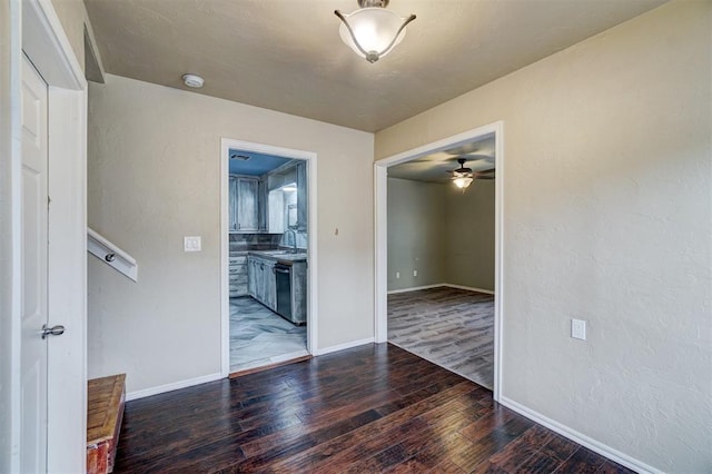 empty room featuring ceiling fan, sink, and dark wood-type flooring