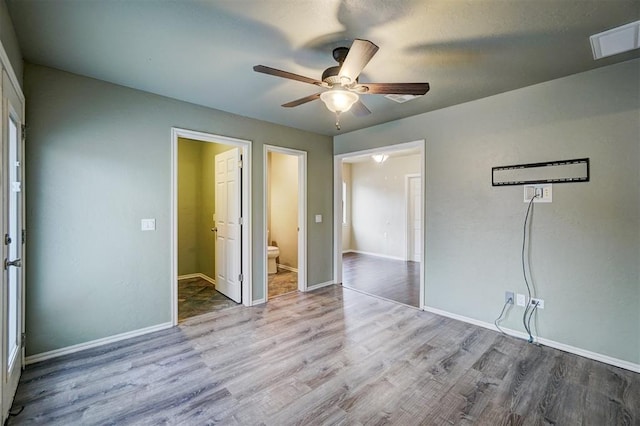 unfurnished bedroom featuring ceiling fan, wood-type flooring, and ensuite bath