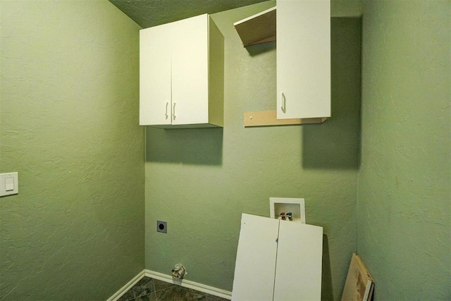 laundry area with hookup for an electric dryer, cabinets, hookup for a washing machine, and dark tile patterned flooring