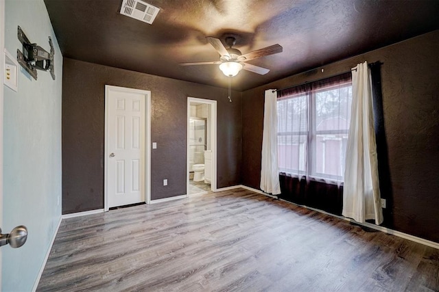 unfurnished bedroom featuring light wood-type flooring, ensuite bathroom, and ceiling fan