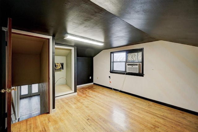 bonus room with light wood-type flooring, cooling unit, and lofted ceiling