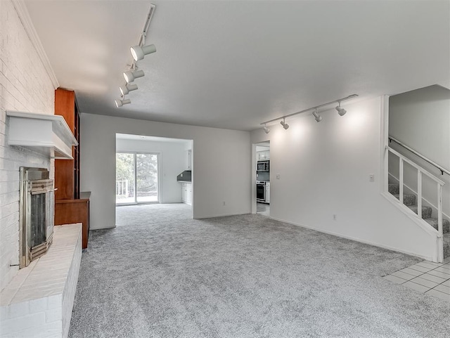6404 Westway, Oklahoma City, OK 73142 - unfurnished living room featuring rail lighting, carpet, a fireplace, and stairs
