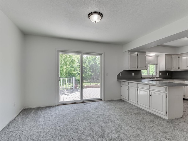 6404 Westway, Oklahoma City, OK 73142 - kitchen with light carpet, a peninsula, and a textured ceiling