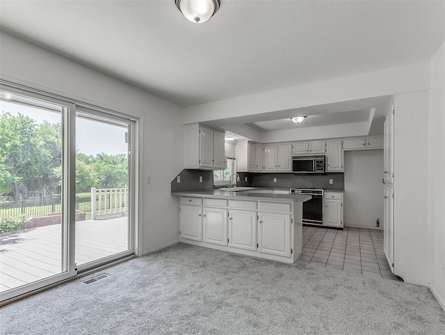 6404 Westway, Oklahoma City, OK 73142 - kitchen with stainless steel microwave, range, a peninsula, light carpet, and light tile patterned floors