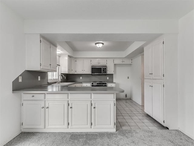6404 Westway, Oklahoma City, OK 73142 - kitchen featuring appliances with stainless steel finishes, a peninsula, white cabinetry, light tile patterned floors, and a raised ceiling
