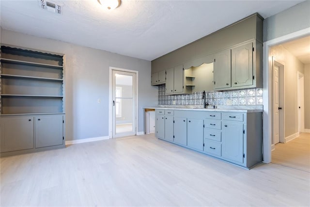 kitchen featuring decorative backsplash, a textured ceiling, light hardwood / wood-style flooring, and sink