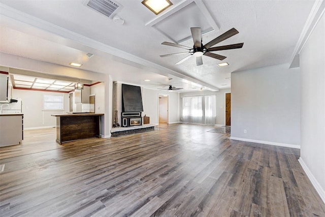 unfurnished living room featuring ceiling fan, wood-type flooring, and a wood stove