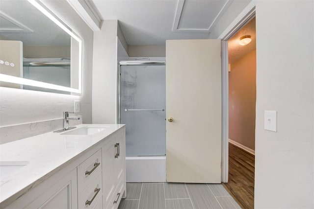 bathroom featuring hardwood / wood-style flooring, vanity, and shower / bath combination with glass door