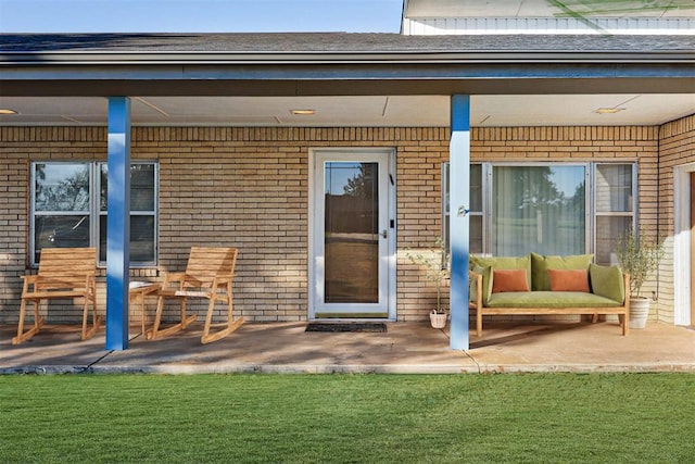 doorway to property featuring a patio and brick siding