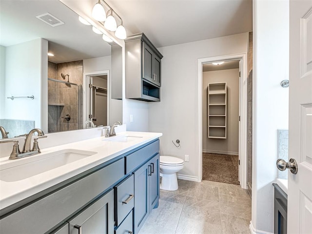 bathroom featuring a tile shower, tile patterned flooring, vanity, and toilet