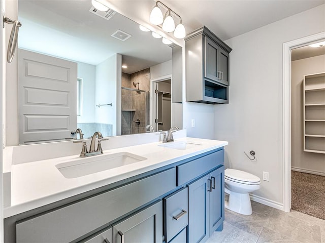 bathroom featuring a tile shower, tile patterned floors, vanity, and toilet