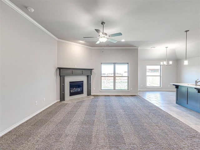 unfurnished living room featuring carpet flooring, ceiling fan with notable chandelier, sink, and crown molding