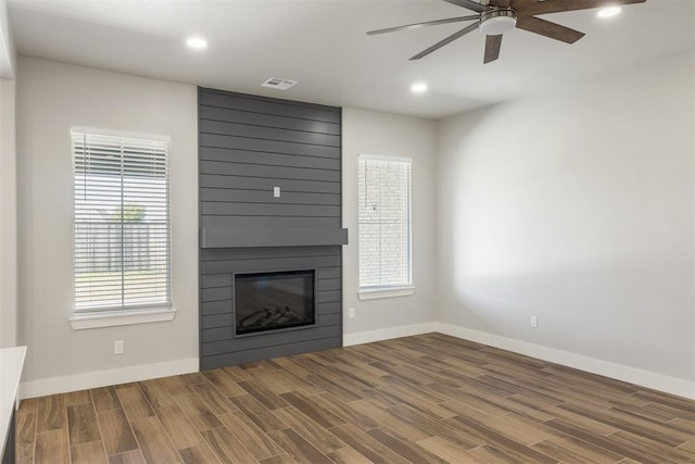 unfurnished living room featuring hardwood / wood-style floors, ceiling fan, and a fireplace