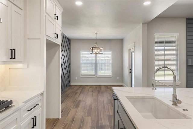 kitchen featuring light stone countertops, white cabinetry, a healthy amount of sunlight, and sink