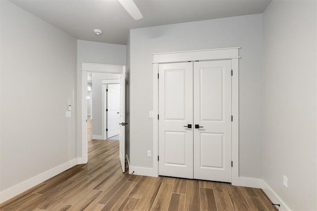 unfurnished bedroom with ceiling fan, wood-type flooring, and a closet