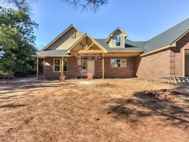 view of front of house with brick siding and roof with shingles