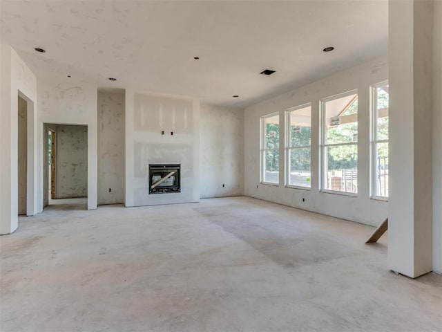 unfurnished living room featuring a glass covered fireplace and concrete flooring