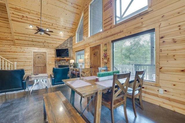 dining space with ceiling fan, beamed ceiling, high vaulted ceiling, wooden walls, and wood ceiling