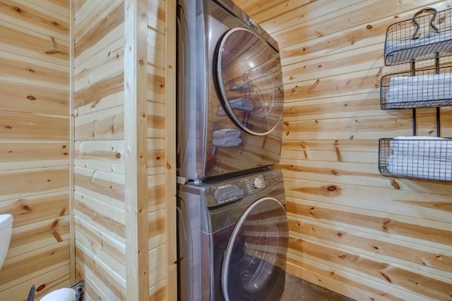 laundry room with wood walls and stacked washer and dryer