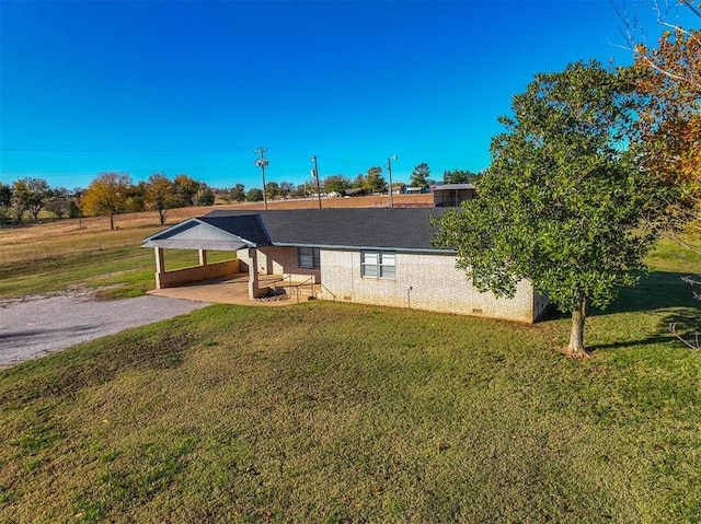 ranch-style house featuring a carport, a front lawn, and a patio area