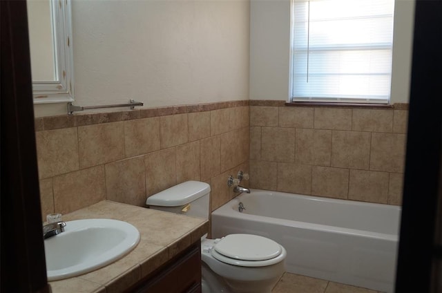 bathroom featuring a tub, sink, tile patterned floors, toilet, and tile walls