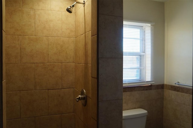 bathroom with a tile shower and toilet