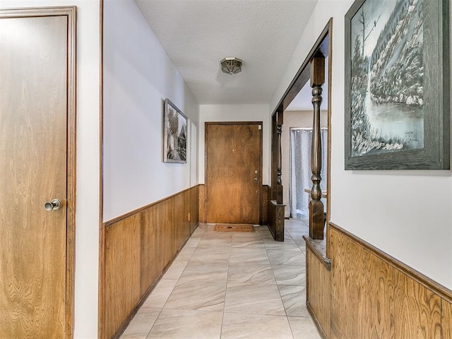 corridor with wood walls and a textured ceiling