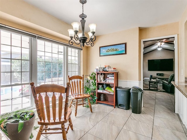 interior space featuring ceiling fan with notable chandelier, vaulted ceiling, and light tile patterned flooring