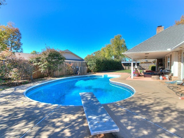 view of pool with ceiling fan, a diving board, and a patio area