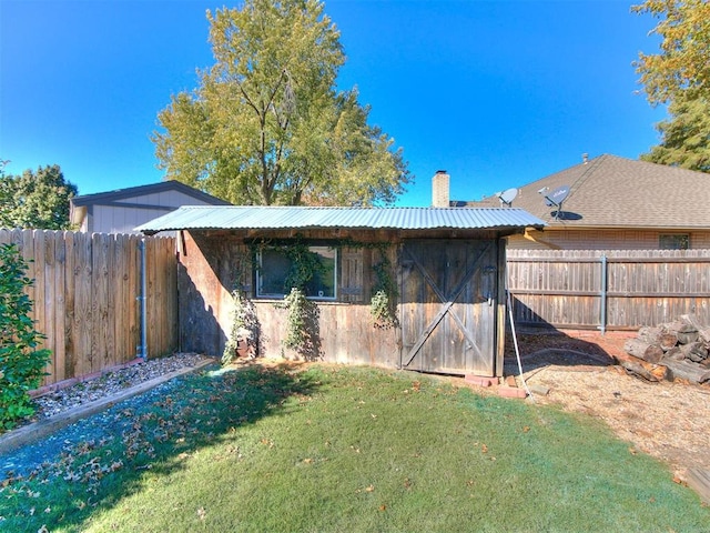 back of house with a storage unit and a lawn