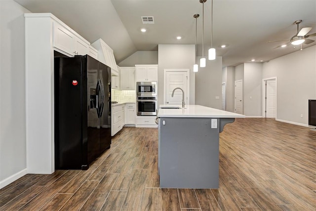 kitchen with white cabinetry, sink, dark wood-type flooring, stainless steel appliances, and a center island with sink